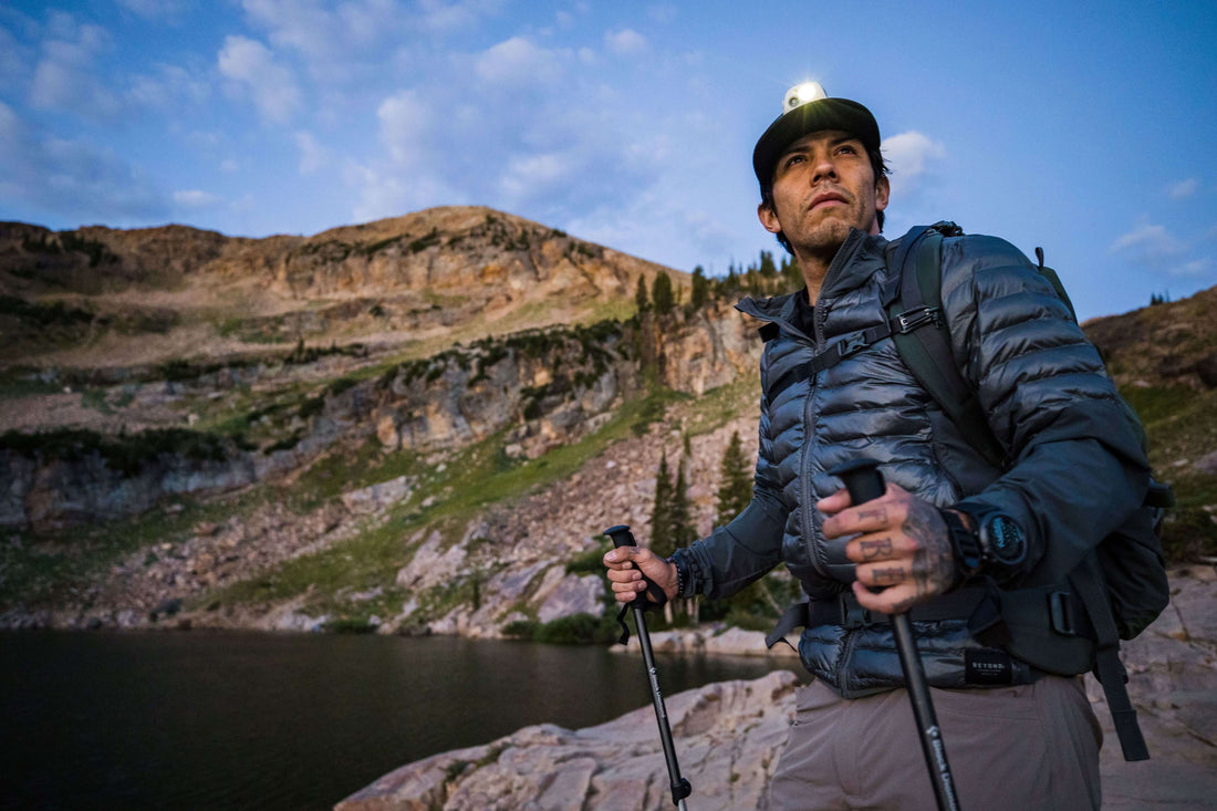 Man wearing Navy Dasche jacket and a backpack with hiking poles on a hike