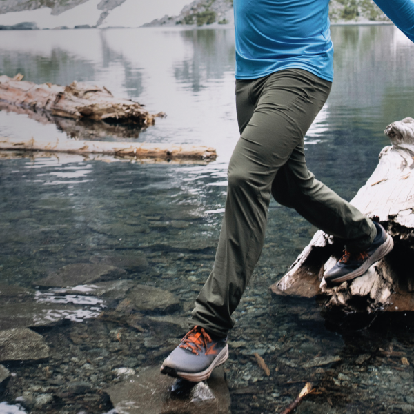 Man walking on a long in a lake wearing the Ascent-Glide pants by Beyond Clothing. 