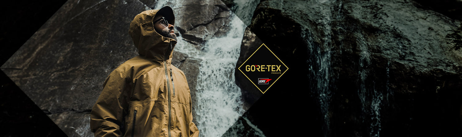 Hiker wearing the Drilight Jacket from Beyond near a water fall. GORE-TEX Fabrics logo shown.
