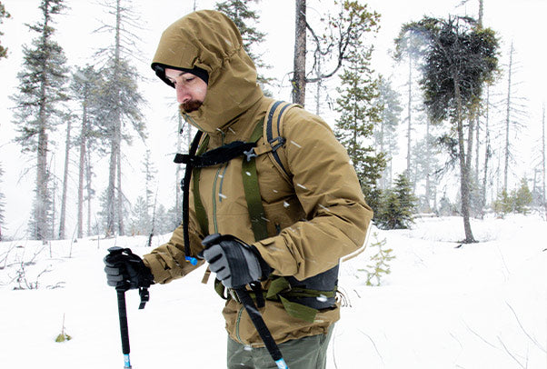 Backcountry Skier wearing the Drilight Rain Jacket while pulling a sled in a snowy field.