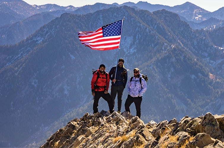 Three Veterans on a mountain peak with an American flag