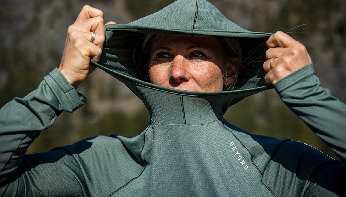woman in Dark Mint Geo T pulling up the hood to block out the sun