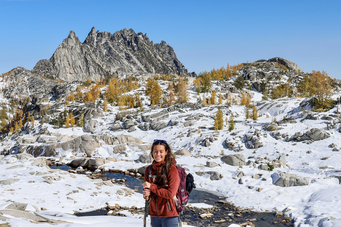 Women wearing the Alpha Aura Jacket, a backpack and carrying trekking poles while hiking the Enchantments.