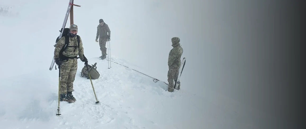Women solider wearing Beyond Clothing on an snowy mountain side with two others with her.