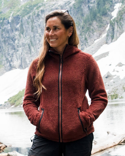 Woman wearing the Alpha Aura Jacket on a hike at an alpine lake.- Beyond Clothing USA #group_mars-red