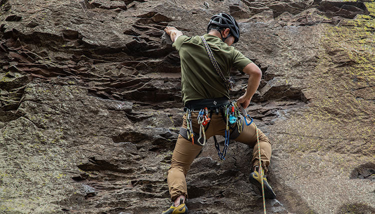 Man rock climbing in the FirstSun Short Sleeve Shirt by Beyond Clothing. 