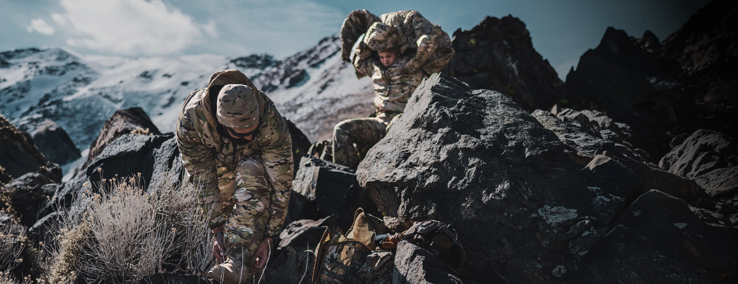 Image of two warfighters layering in the mountains while wearing Beyond Clothing.