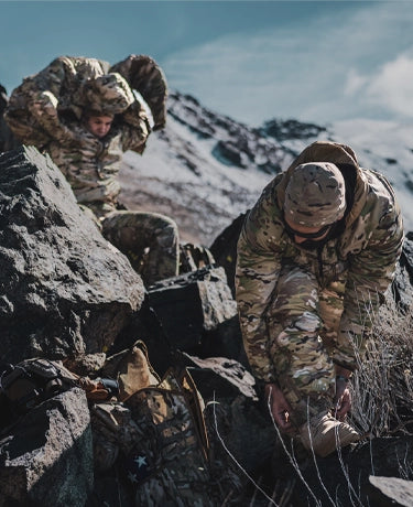 Image of two warfighters layering in the mountains while wearing Beyond Clothing.
