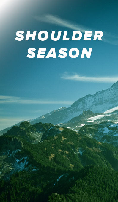 A scenic mountain landscape with snow patches, evergreen forested slopes, and a blue sky. Large white text at the top reads “SHOULDER SEASON. This is 1 of the 3 image collage of Mount Rainer.