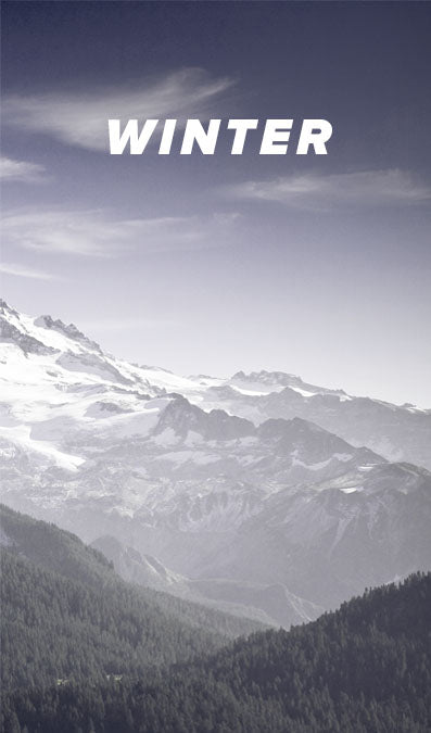 A scenic winter mountain landscape with snow-covered peaks, dark forested slopes, and the word 