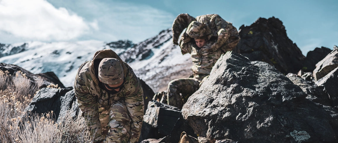 Two warfighters on a rocky mountain side.