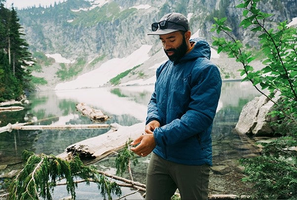 Man wearing Steel Blue Ultra Lochi 2.0 in front of a lake adjusting the waist cuffs