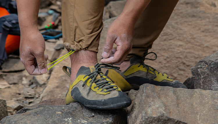 Rock Climber showing off the integrated gaiter of the TarnGood pant in Tobacco. His hands are chalked up and he is wearing climbing shoes.