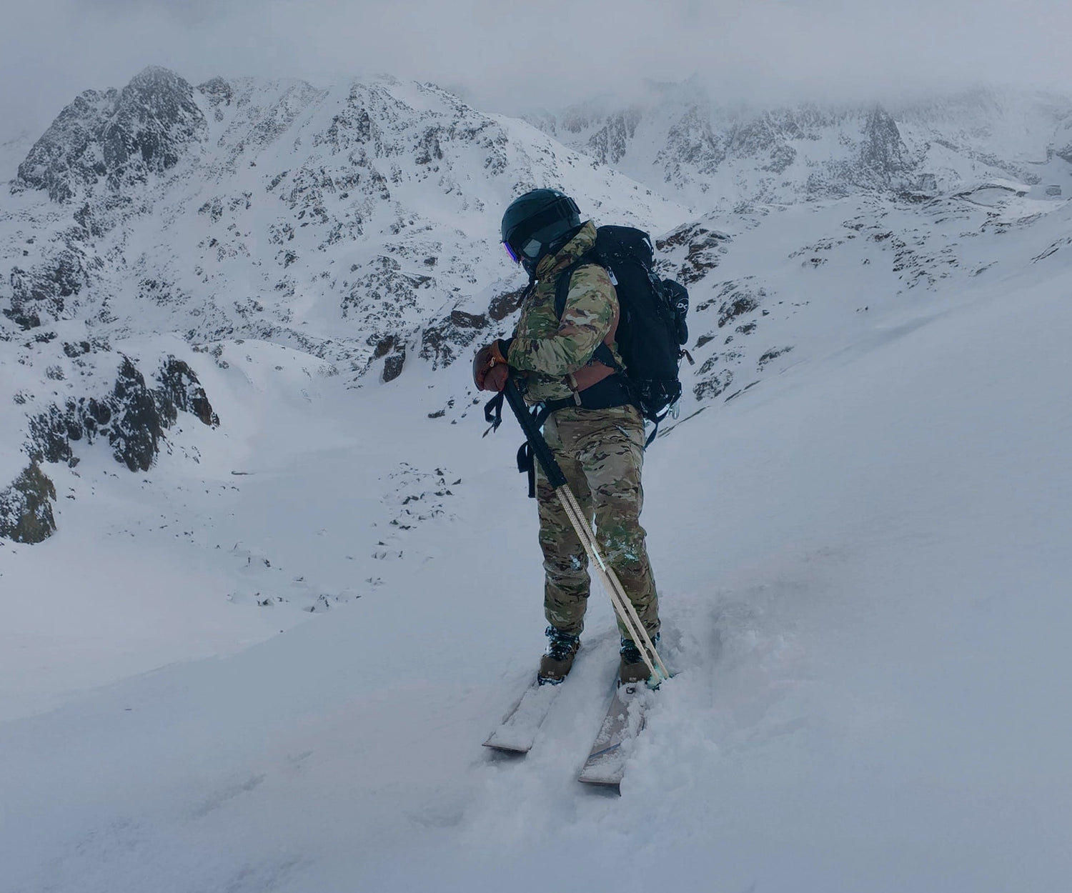 Person skiing up a snowy mountain with backpack and skis