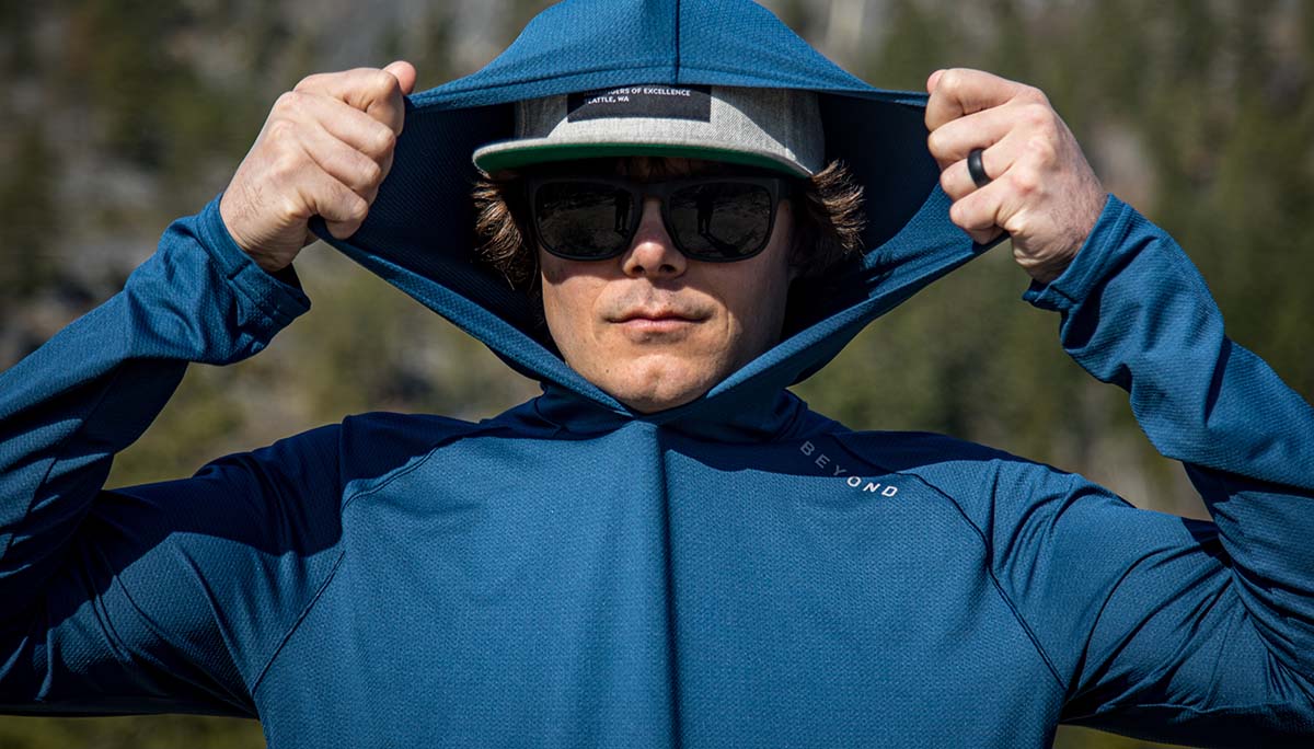 Man wearing Steel Blue Hooded Geo T LS Shirt showcasing the stretchy hat compatible hood